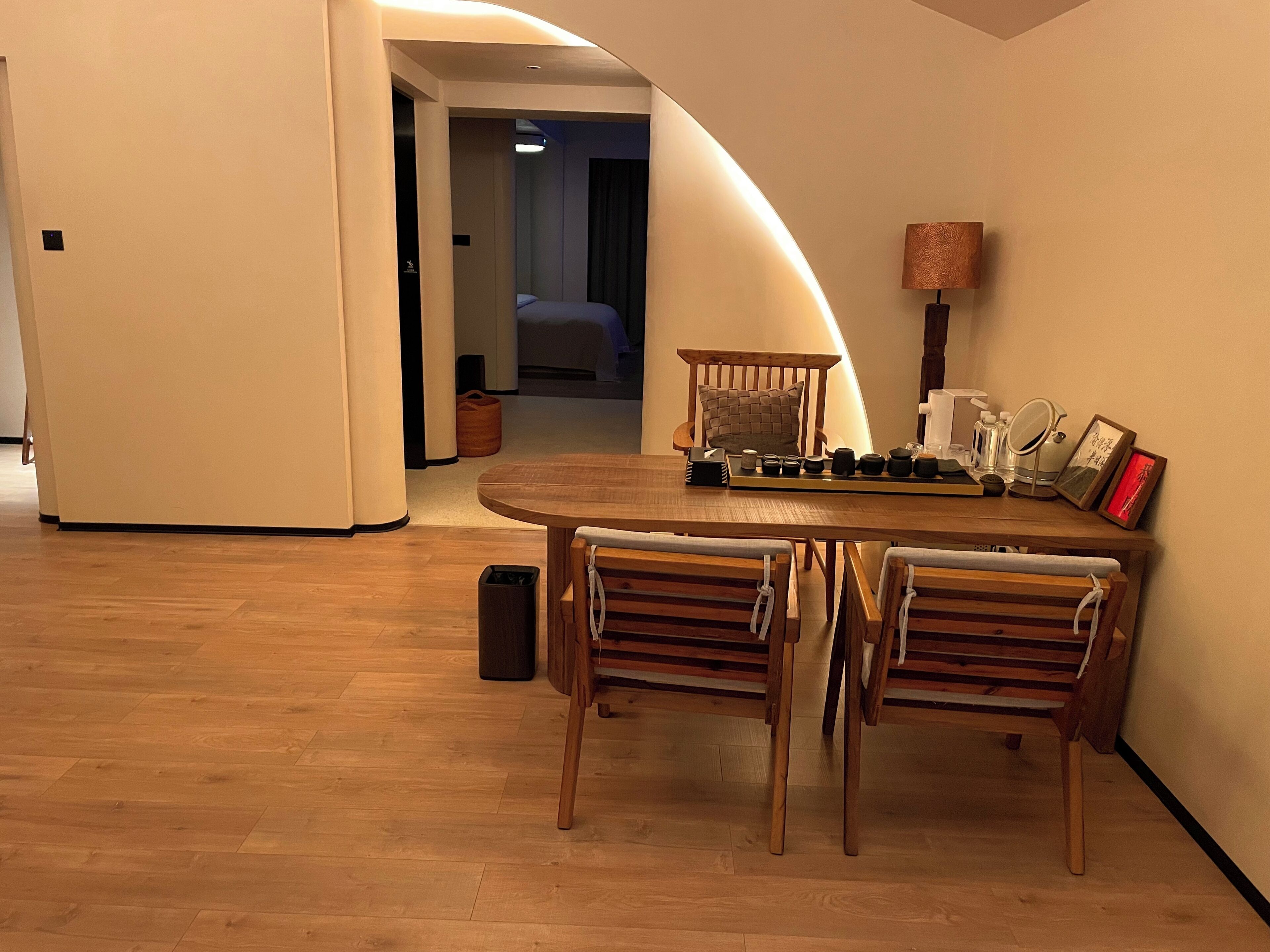 A dining area with a round table and four chairs, a lamp, and a small cabinet.
