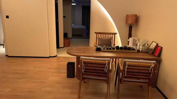 A dining area with a round table and four chairs, a lamp, and a small cabinet.