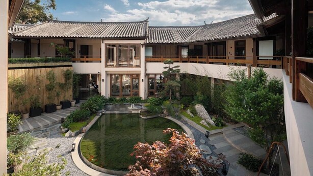 A traditional Japanese-style courtyard with a central pond, wooden walkways, and potted plants. - Lijiang Garden vacation PuZhi hotel (Lijiang)
