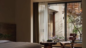 A modern bedroom with a large window, a wooden nightstand, a chair, and a bed. - Lijiang Garden vacation PuZhi hotel (Lijiang)