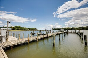 A wooden pier extending into a calm body of water, surrounded by greenery and a clear sky. - Sunrise Landing: Waterfront Cottage in Avenue! (Avenue)