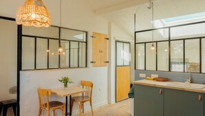 A kitchen with wooden cabinets, a dining table with chairs, and pendant lighting. - Charming studio in lovely Les Vans, National Park Monts d'Ardèche, river nearby. (Les Vans)