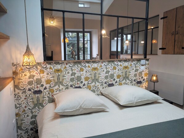A bedroom with a floral-patterned headboard, two pillows, and a bedside lamp.