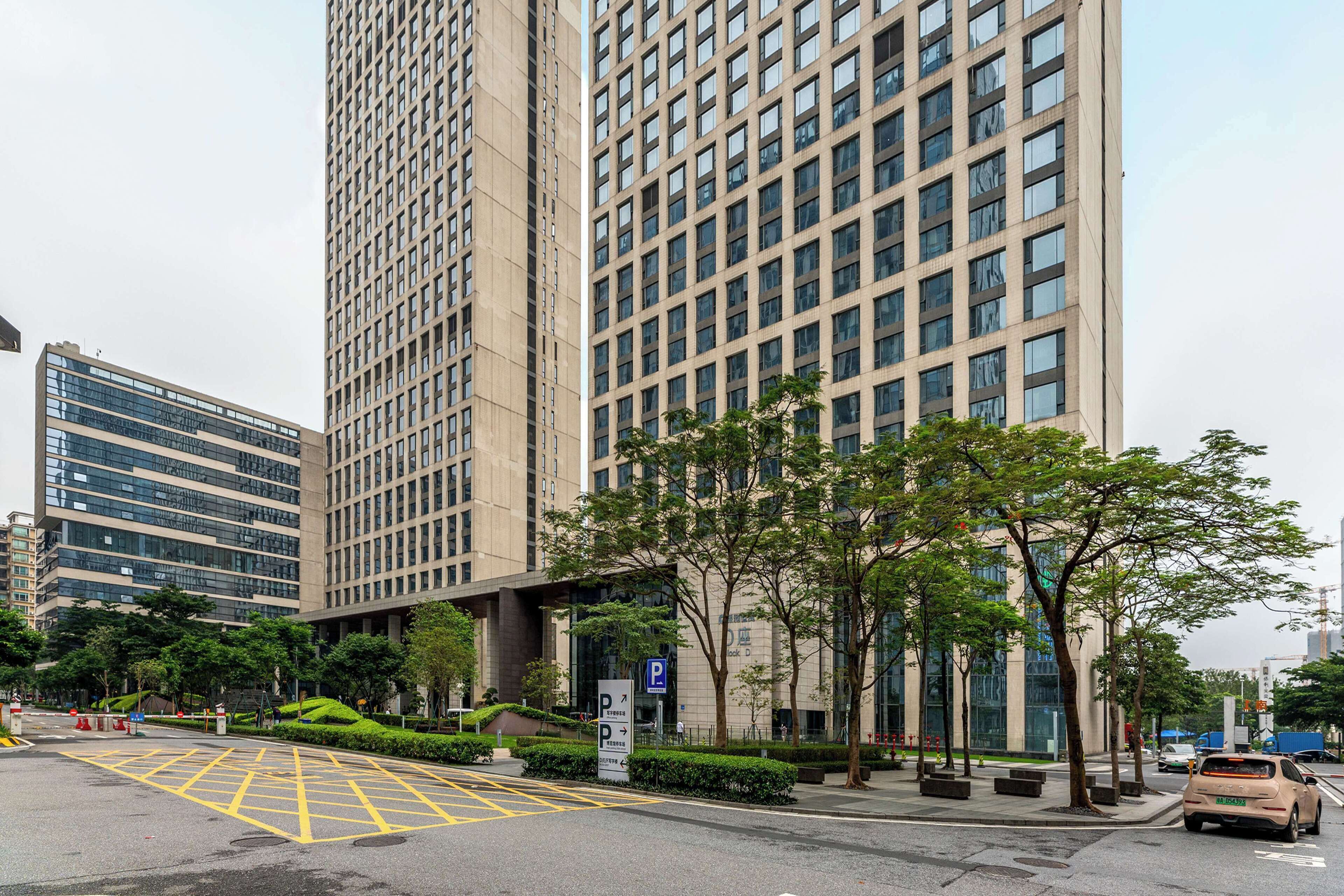 A modern urban street with tall buildings, a parking sign, and a car.