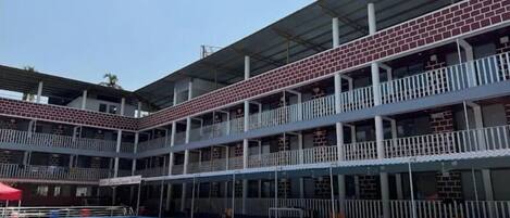 Un immeuble à plusieurs étages doté d’une piscine, de balcons et d’un espace couvert.