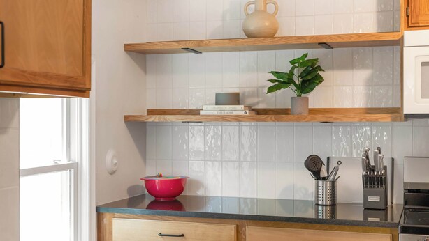 Una cocina con armarios de madera, un microondas, una estufa y una encimera con un bol y utensilios.