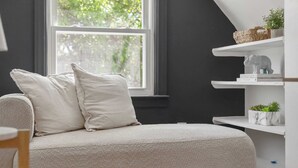 Una habitación acogedora con un sofá, almohadas, una ventana y estantes decorados con objetos ornamentales.