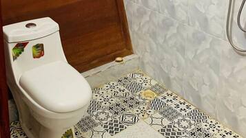 Une petite salle de bain avec des toilettes, une douche et des carreaux décorés.