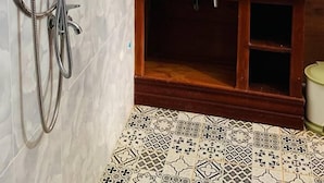 A bathroom with a shower, a sink, and a wooden cabinet.