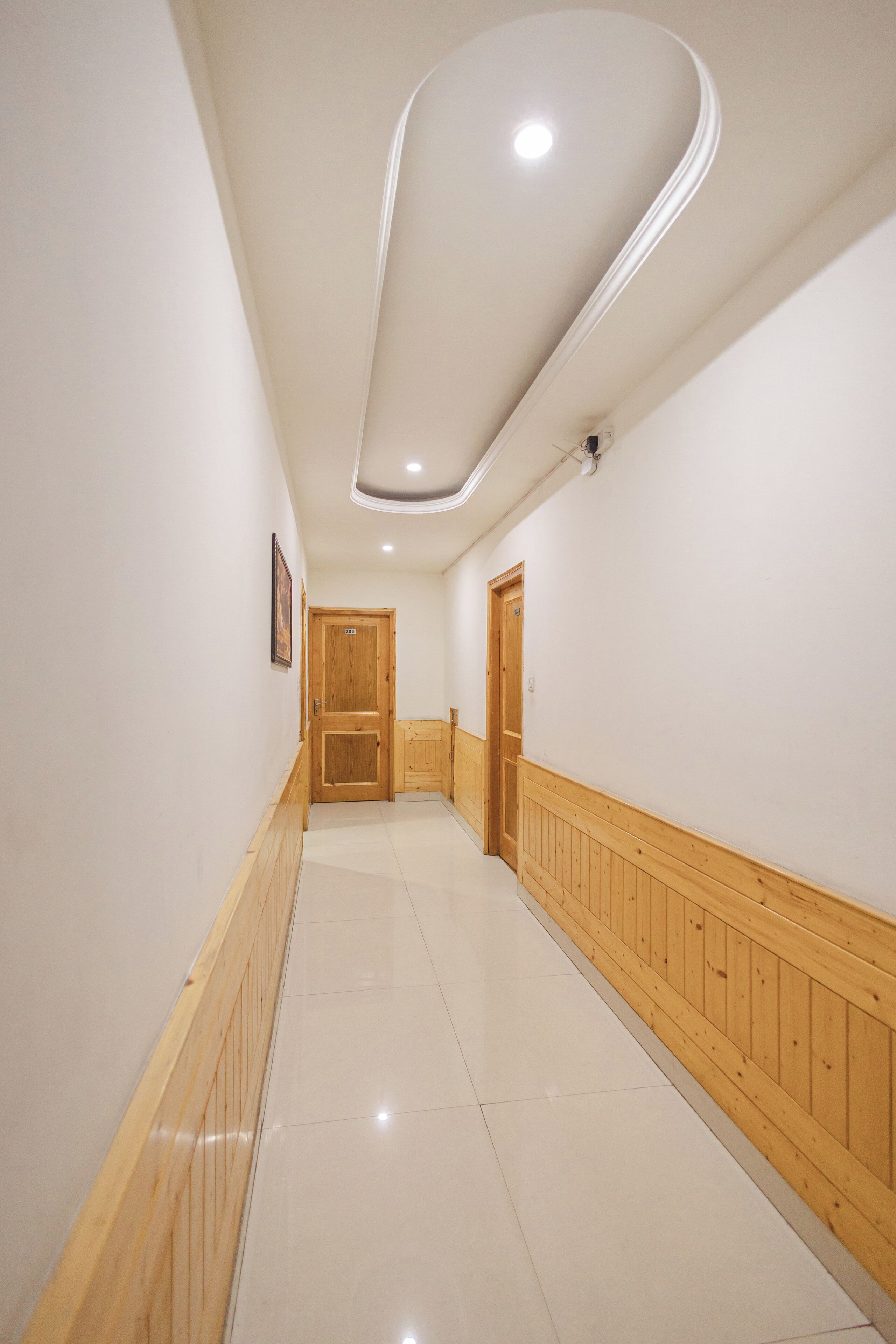 A hallway with wooden paneling, a tiled floor, and a ceiling light fixture.
