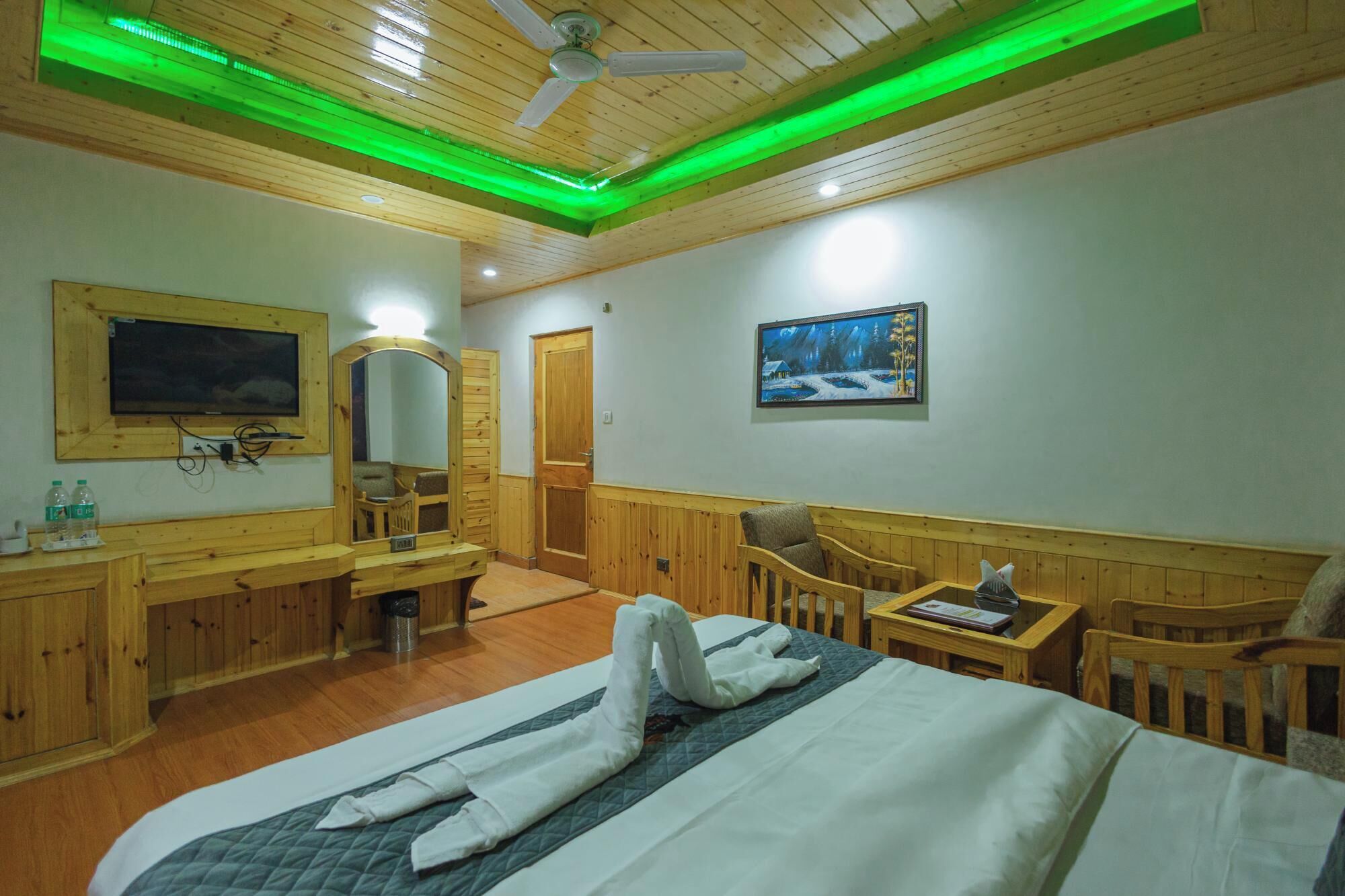 Habitación de hotel con cama, escritorio, silla, televisor y un cuadro en la pared.