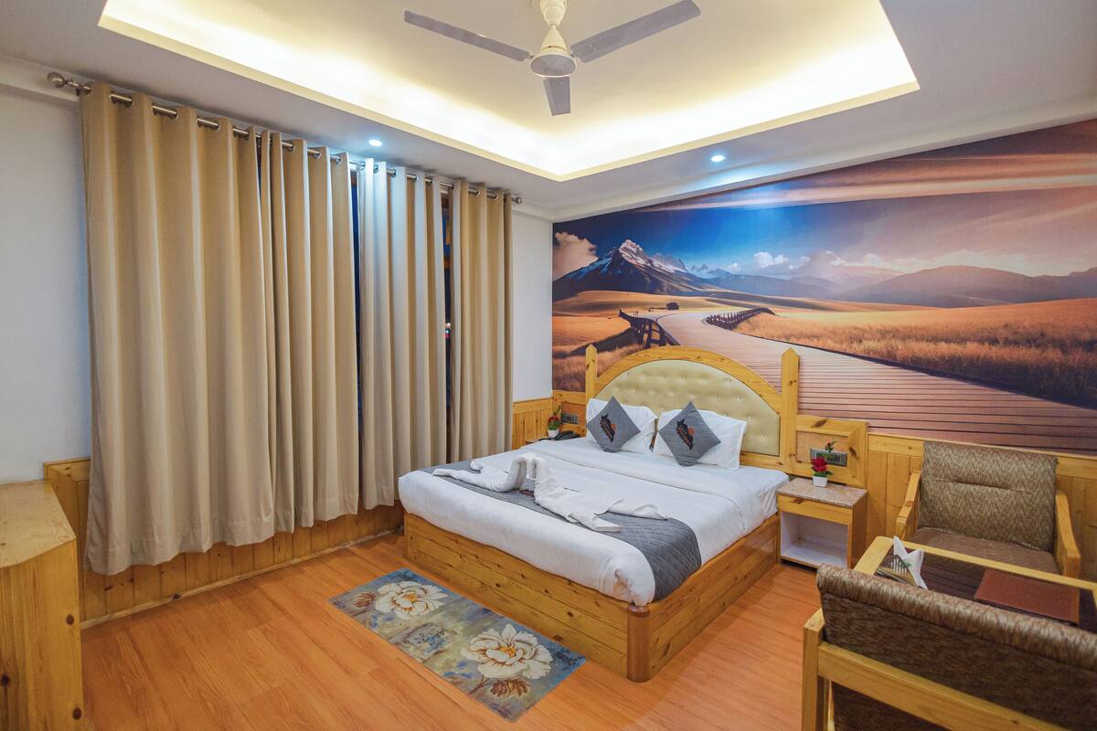 A bedroom with a wooden bed, a nightstand, a chair, and a mural of a desert landscape.