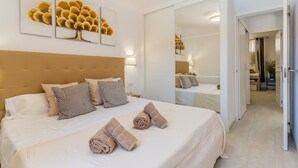 Quarto de hotel com uma cama grande, cabeceira, espelho e obras de arte na parede.