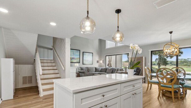 A modern kitchen with a central island, white cabinetry, and pendant lighting.