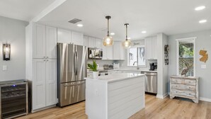 A modern kitchen with white cabinetry, stainless steel appliances, and pendant lighting.