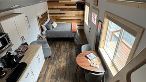 Une chambre compacte et moderne, dotée d’un lit en mezzanine, d’une petite kitchenette et d’un coin repas offrant une vue sur l’extérieur.