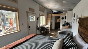Une chambre à coucher avec un lit, un bureau et une chaise. Il y a une fenêtre et une porte.