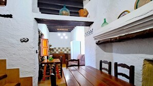 A rustic interior with a wooden dining table, chairs, and a kitchen area in the background. - Suitur rural House Cortijo de Don Manuel ( Grandparents) (Granada Algarinejo)