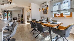 A modern dining area with a wooden table, grey upholstered chairs, and pendant lighting. - Villa Bella by Villas Guide (Vodnjan)