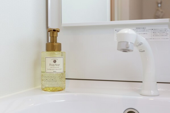 Un lavabo de salle de bain avec un flacon de savon mousse et un robinet.