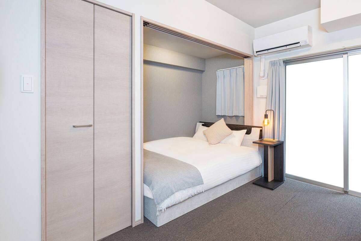 A hotel room with a bed, a nightstand, a mirror, and a sliding door closet.