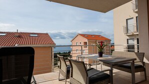 A balcony with wicker furniture, a table, and a potted plant. - Apartman Olivera-Trogir by Villas Guide (Seget Donji)