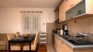 A compact kitchen with a dining area, a built-in oven, and a dishwasher. - Apartman Olivera-Trogir by Villas Guide (Seget Donji)