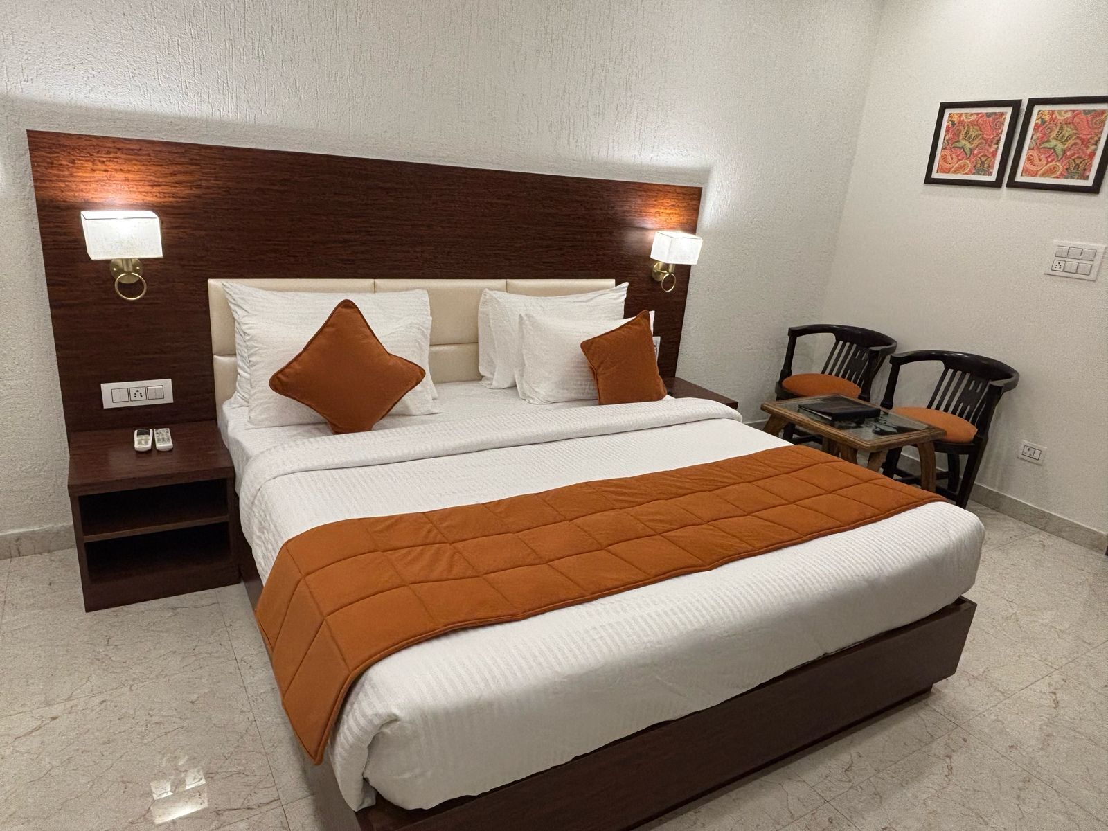 A neatly made bed with a brown quilt, white pillows, and a wooden headboard with wall-mounted lights.