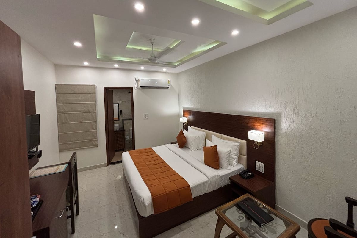 Una habitación de hotel con cama, mesita de noche, lámpara y televisión.