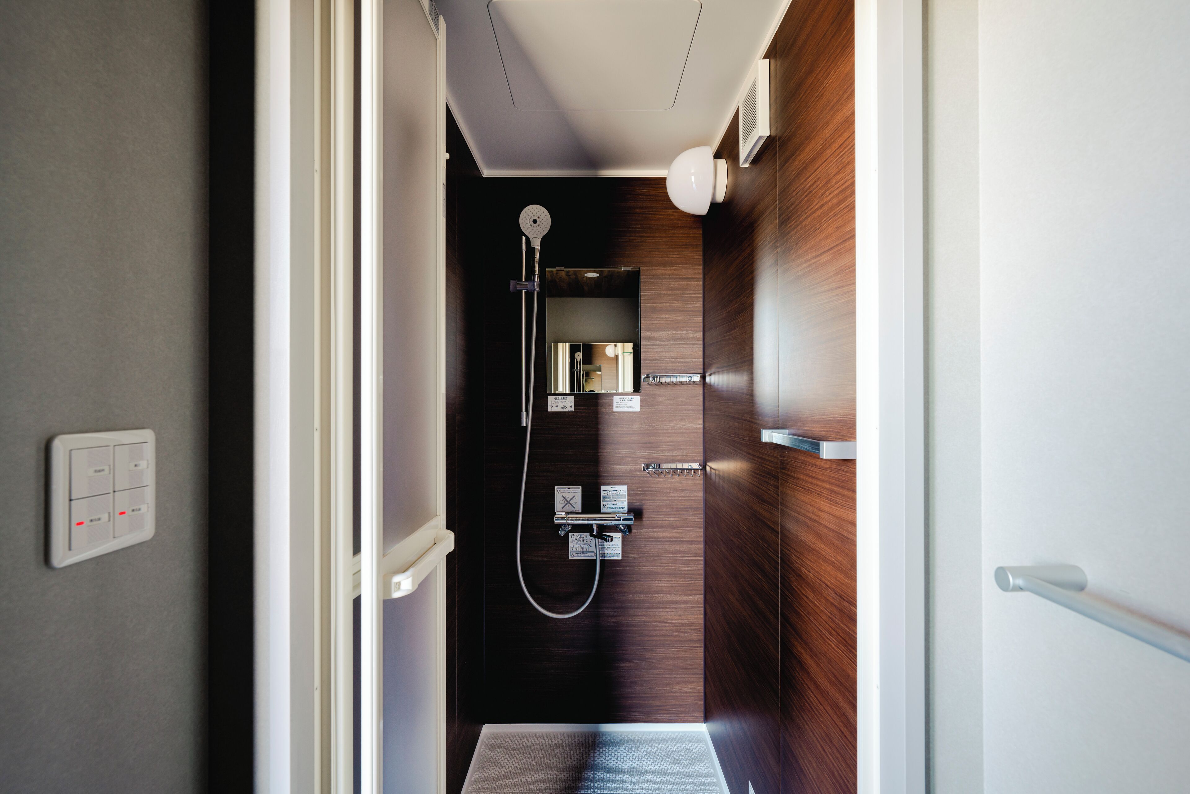 A modern bathroom with a shower, a mirror, and a towel rack.