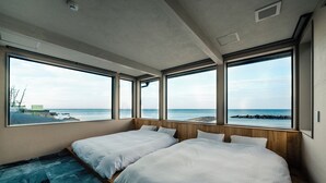 A room with two beds, large windows, and a view of the sea. - UMITOMA OCEAN VIEW RESORT ECHIZEN (Fukui)