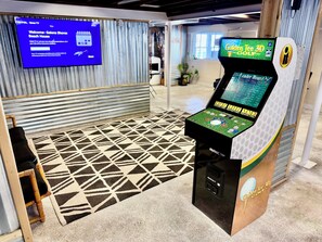 A 3D golf arcade game, a patterned rug, and a TV screen displaying a welcome message.