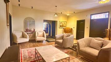 Una sala de estar con un sofá, sillones, una mesa de centro y un tapete estampado.