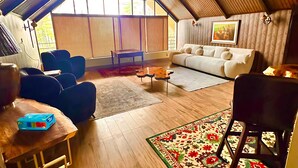 Un loft espaiós amb un sostre alt, bigues de fusta, una finestra gran, un sofà, una taula de cafè i una zona de menjador.