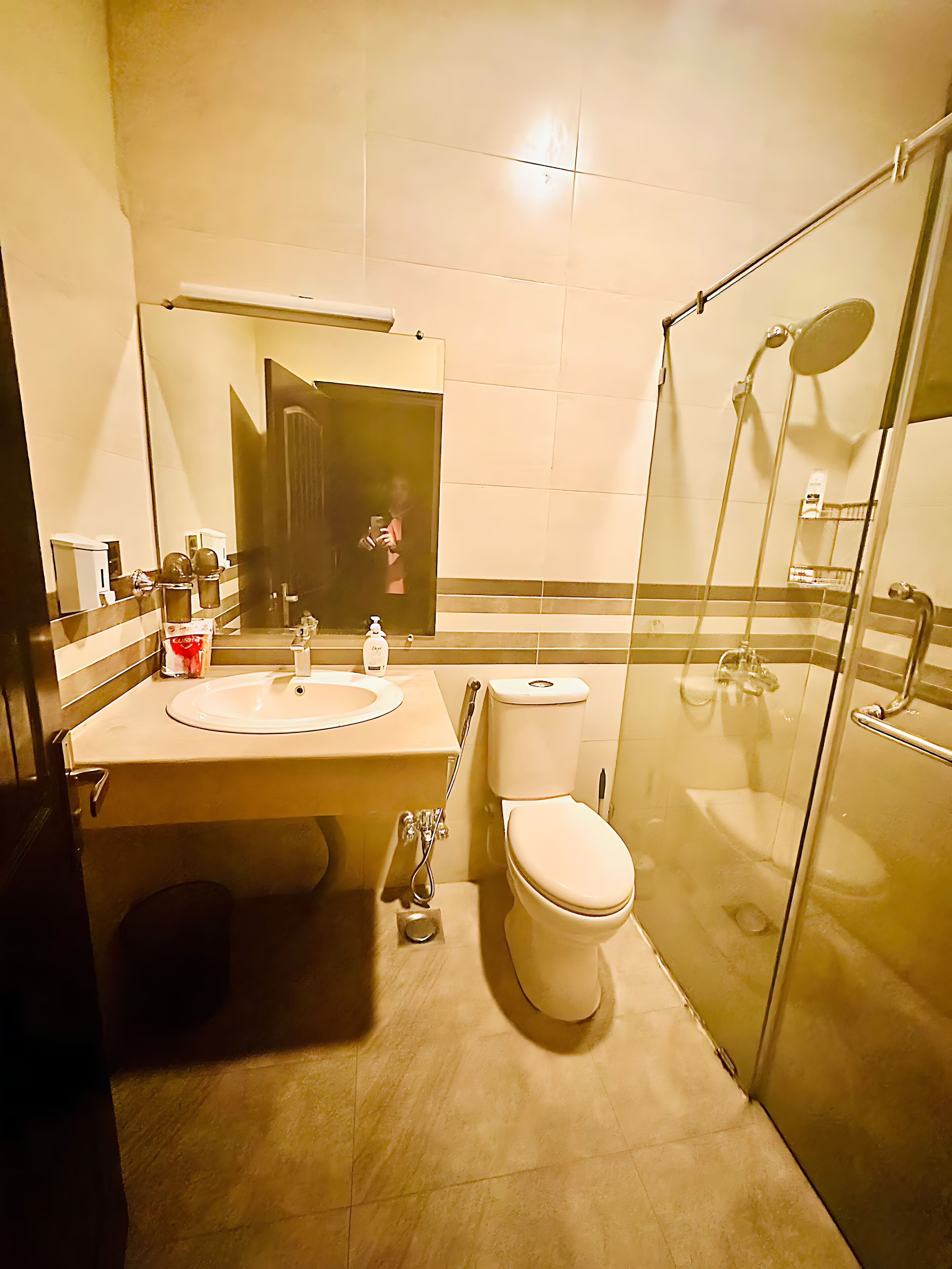 Un baño con lavamanos, inodoro y ducha con mampara de vidrio.