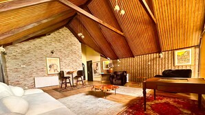 Un espai vital d'estil loft acollidor, amb sostre inclinat, bigues de fusta a la vista, un mur de pedra i una combinació de mobiliari modern i clàssic.
