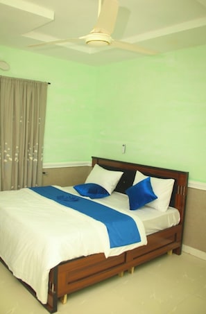 Un dormitorio con cama, ventilador de techo y ventana con cortinas.