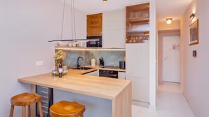 Una cocina moderna con una isla central, taburetes de bar y un horno empotrado.