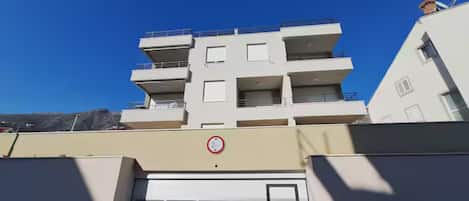 A multi-story residential building with balconies, a garage door, and a no-parking sign.
