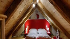 Een slaapkamer met een rode sprei, twee nachtkastjes met lampen en een klein decoratief object op de vloer.