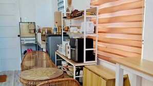 A compact kitchen with a wooden countertop, wicker chairs, and a built-in shelf unit.