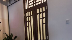 Une pièce avec deux chaises en bois, une grande fenêtre ornée de panneaux de verre décoratifs et une plante en pot.