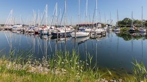 A marina with multiple sailboats docked, surrounded by calm water and greenery. - Beach House Westkapelle 105.1 by Interhome (Westkapelle)