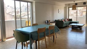 Un salon spacieux avec un coin repas, de grandes fenêtres et un balcon.