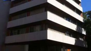 Un immeuble à plusieurs étages doté d’une architecture moderne, caractérisé par des lignes horizontales et des balcons.