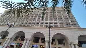 A multi-story building with a modern architectural design, featuring a series of balconies and a large entrance with arched columns. - Villa Vistosa Omaxe Hazratganj (Lucknow)