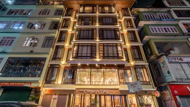 A multi-story building with a sign reading "ORIENTAL" at the ground level, featuring large windows and a traditional architectural style. - The Oriental (Gangtok)