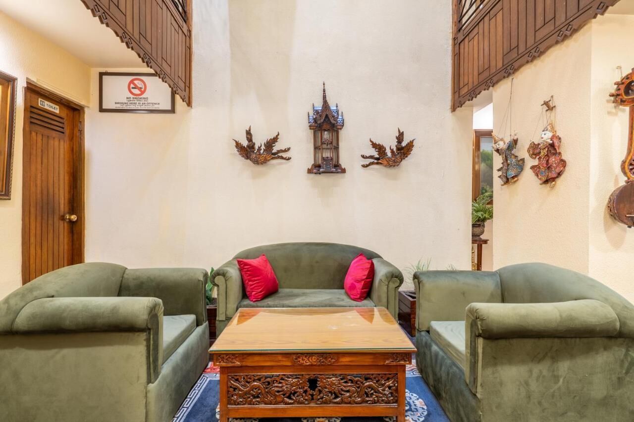 Une pièce comprenant un canapé vert, une table basse en bois et des éléments de décoration murale, notamment une lanterne et deux figurines d’oiseaux.