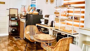 A kitchen with a dining area, featuring a wooden floor, wicker chairs, and a white table.