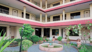 A multi-level building with a courtyard featuring a central fountain, surrounded by potted plants and a tiled floor. - Kohloy Golden Park (Tak)